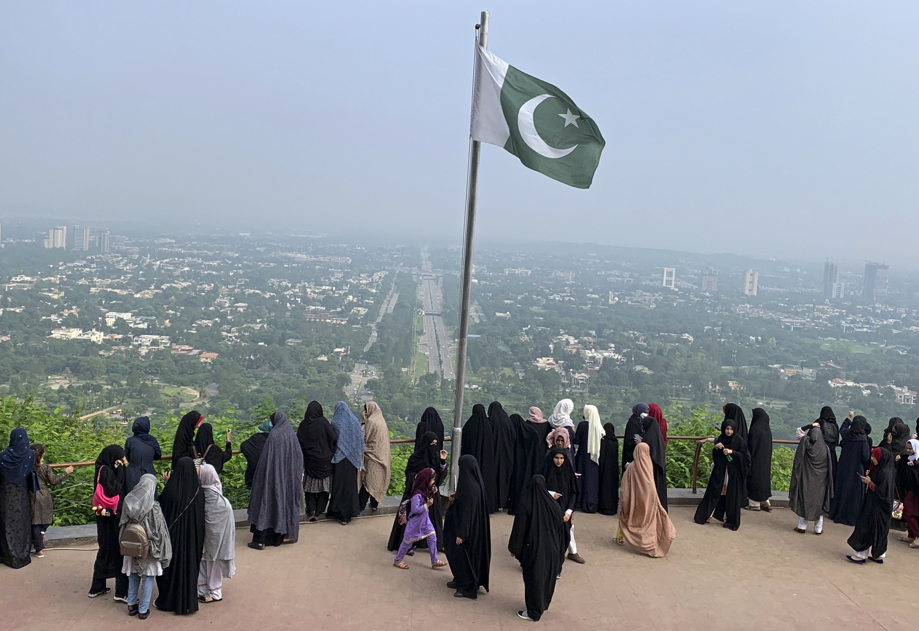 A Pakistani flag flies on a lookout as women take in the view of Islamabad, Pakistan, July 27, 2022. (AP Photo)